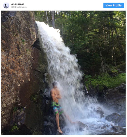 Man standing under natural waterfall to cool off