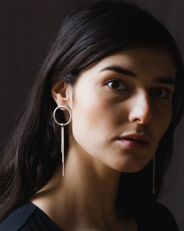 Woman wearing a solis hoop earring with a dark background